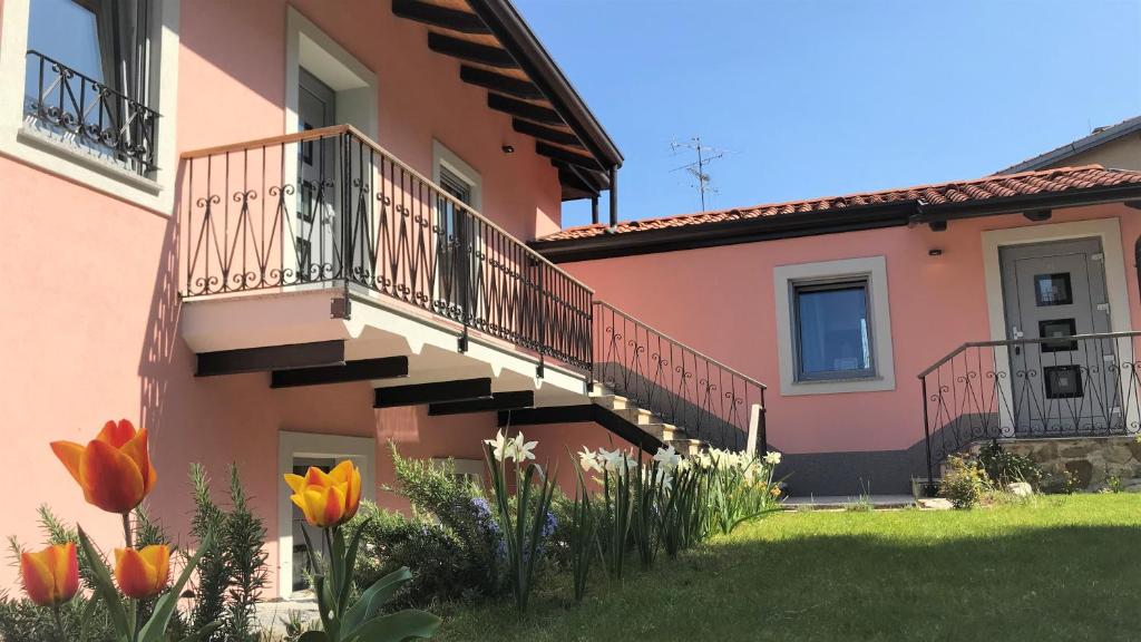 une maison rose avec des escaliers et des fleurs dans la cour dans l'établissement Vila Burbonka, à Nova Gorica