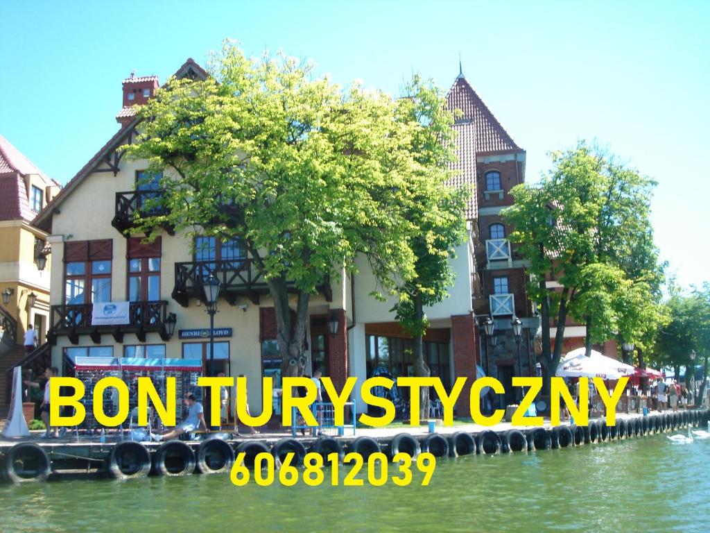 a building on a river with a sign that reads bon tivoliasy at Apartamenty Nowe Mikołajki in Mikołajki