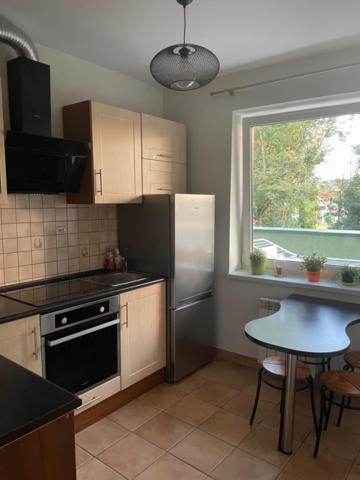 een keuken met een koelkast, een tafel en een raam bij Apartament Podłęska in Krakau