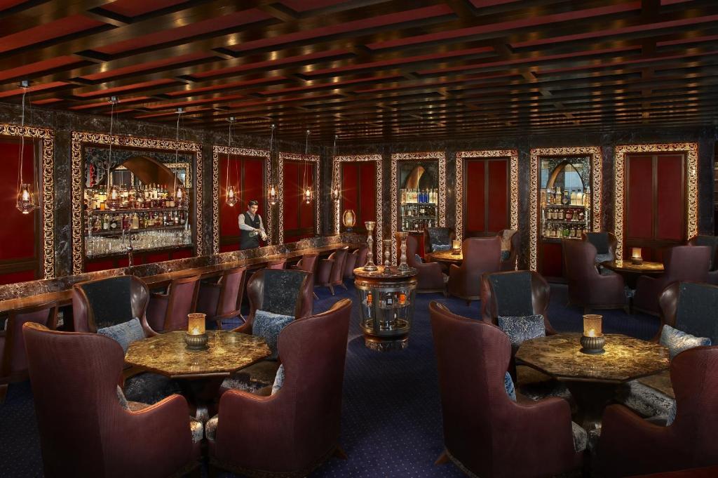 a bar with chairs and tables in a room with red walls at The Leela Ambience Gurugram Hotel & Residences - The Luxury Urban Sanctuary in Gurgaon