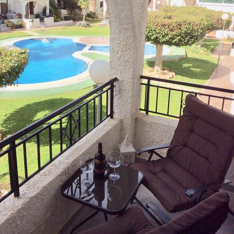 a balcony with a chair and a table with a bottle of wine at Oleza Garden - Laguna Rosa - Playa Flamenca - Pool & Garden View. in Playa Flamenca