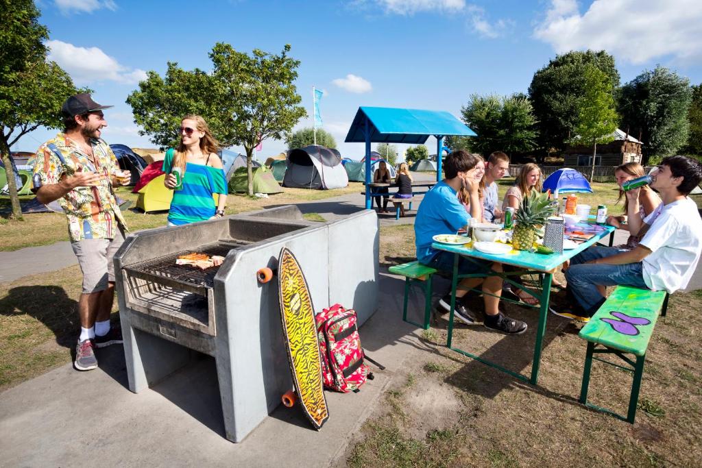 a group of people sitting at a table with a grill at Camping Zeeburg Amsterdam in Amsterdam