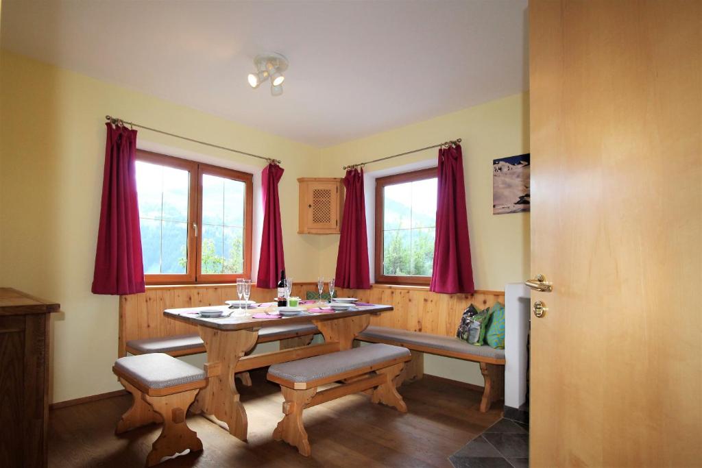 une salle à manger avec une table en bois et des rideaux rouges dans l'établissement Lodge Pengelstein by Apartment Managers, à Kirchberg in Tirol