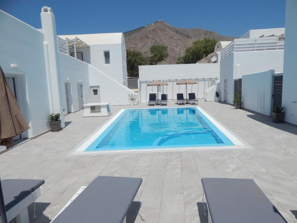 a swimming pool on a patio with white buildings at Petra Aqua Villa in Perissa