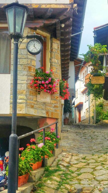 a clock on the side of a building with flowers at Family Hotel "Slavianska dusha" - FREE PARKING in Veliko Tŭrnovo