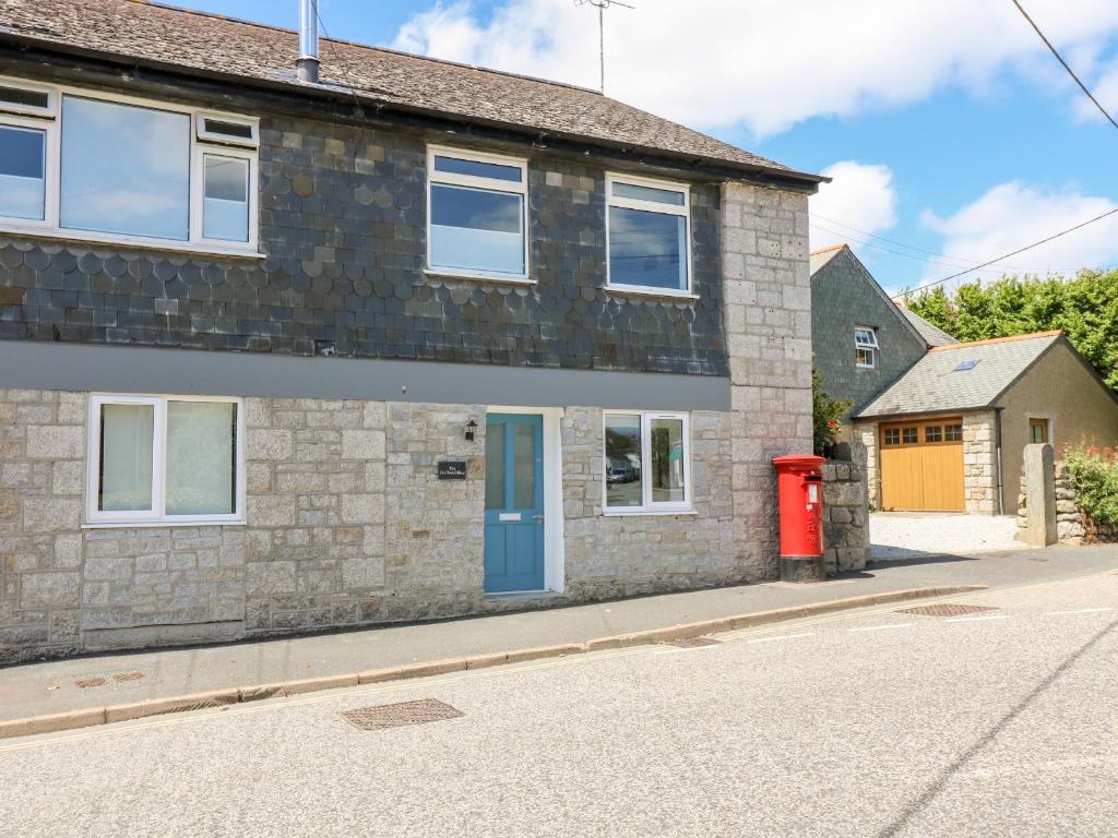 a brick house with a blue door and a red mailbox at Rock Pool House in Helston