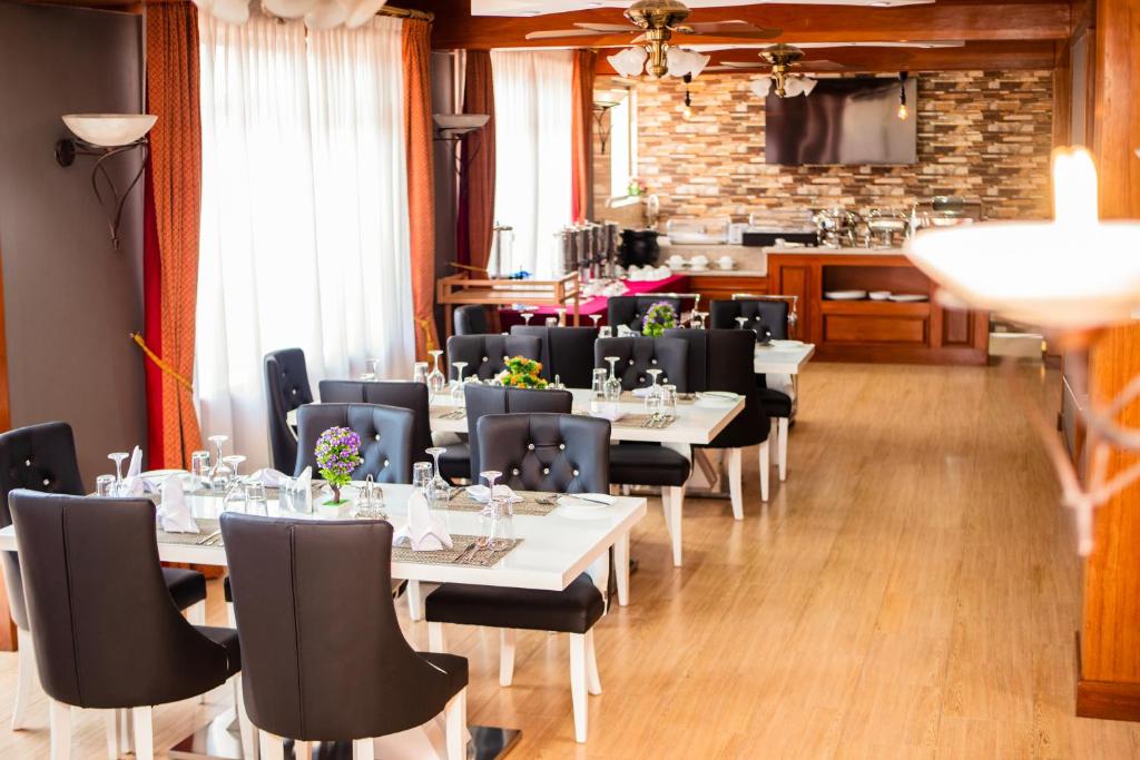 una sala da pranzo con tavoli bianchi e sedie nere di LEYSHOF HOTEL a Mwanza