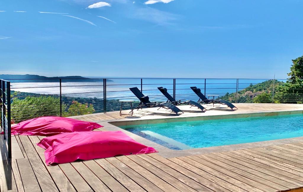 a swimming pool with chairs on a deck next to the water at Découvrez la Villa « The View » in Cavalaire-sur-Mer