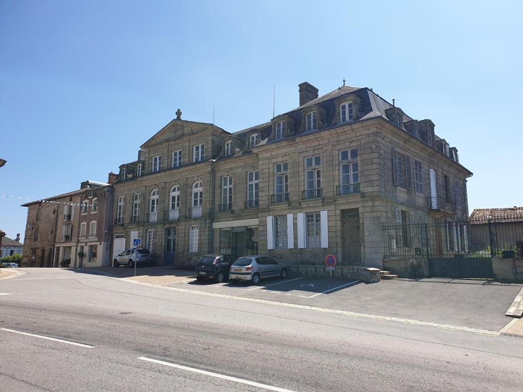 un gran edificio de ladrillo con coches estacionados frente a él en Le Chateau, en Châteauponsac