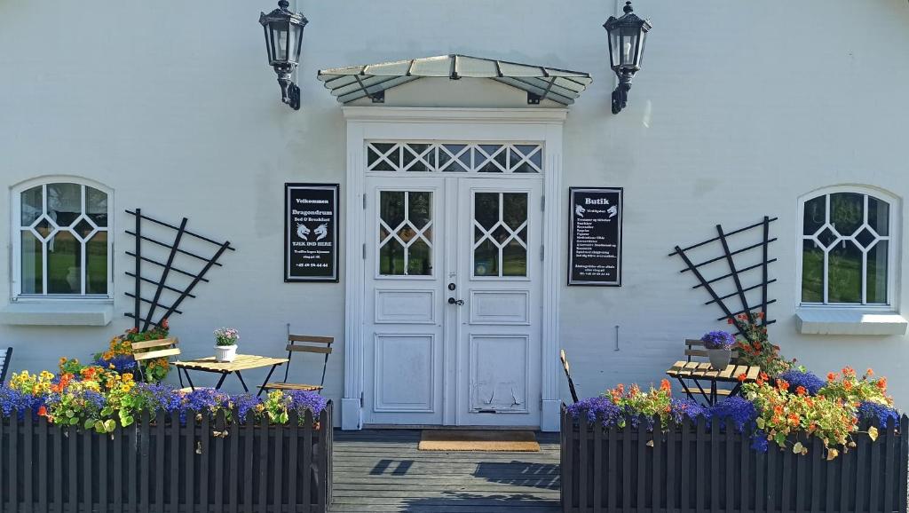 a white front door of a white house with flowers at Dragondrum Bed & Kitchen in Ullerslev