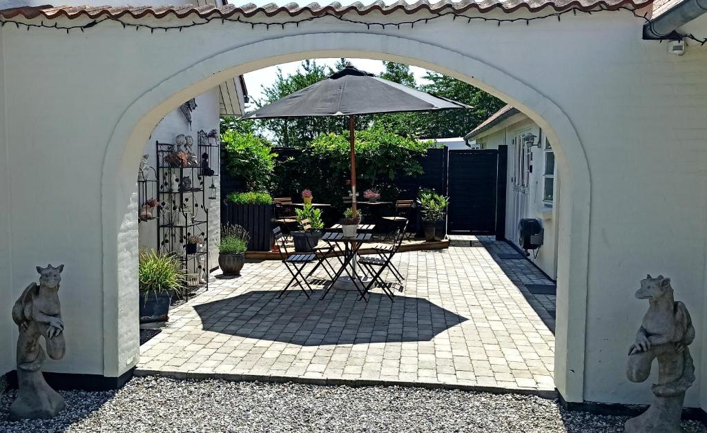 an archway with a table and an umbrella on a patio at Dragondrum Bed & Kitchen in Ullerslev