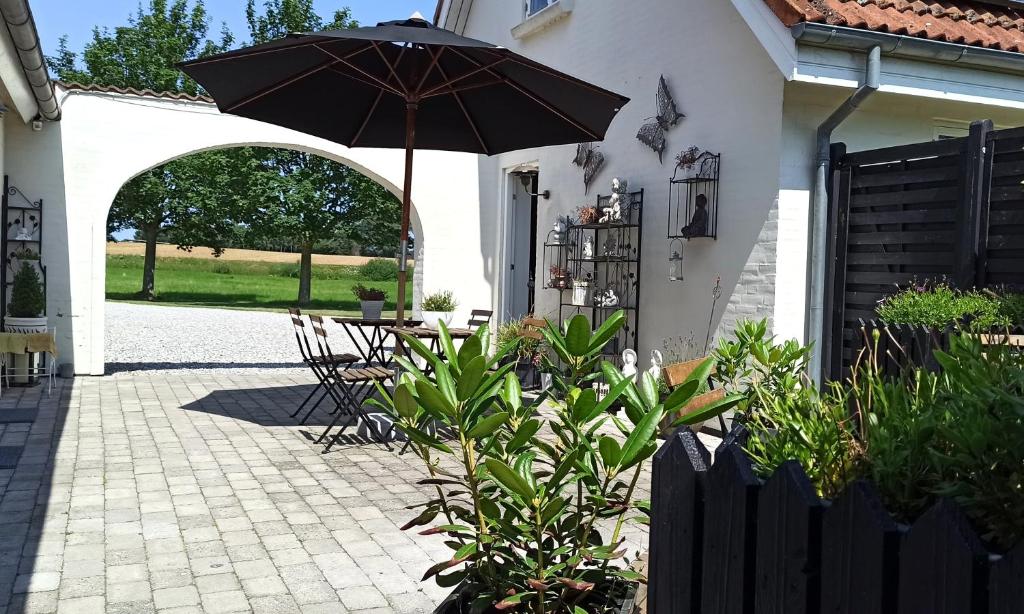 a patio with an umbrella and a table and chairs at Dragondrum Bed & Kitchen in Ullerslev