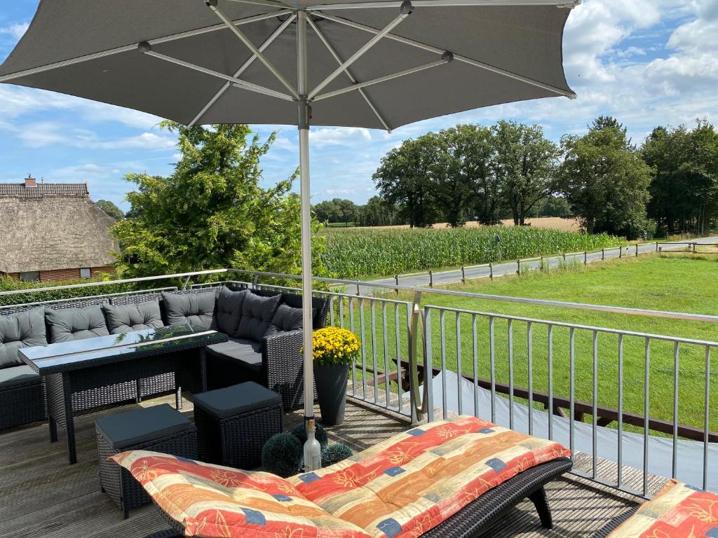 a patio with a couch and an umbrella on a deck at Landhaus Galke in Hude