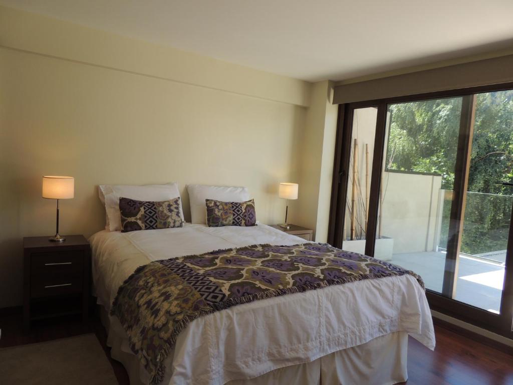 a bedroom with a bed and a large window at Abedul Apartamentos in San Martín de los Andes