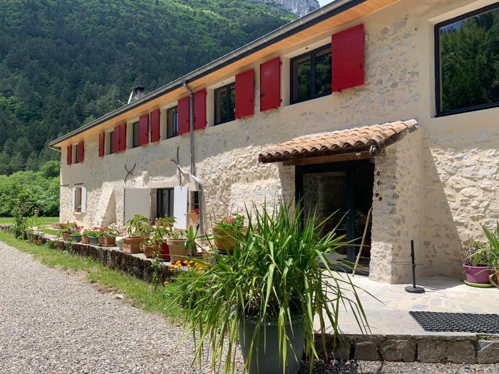 a building with red windows and plants in front of it at La Bergerie à Menée in Châtillon-en-Diois