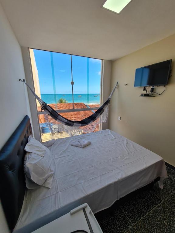 um quarto com uma cama e uma janela com uma rede de descanso em Suites Jangadeiro Maragogi 1 RUA JANGADEIROS 215 em Maragogi