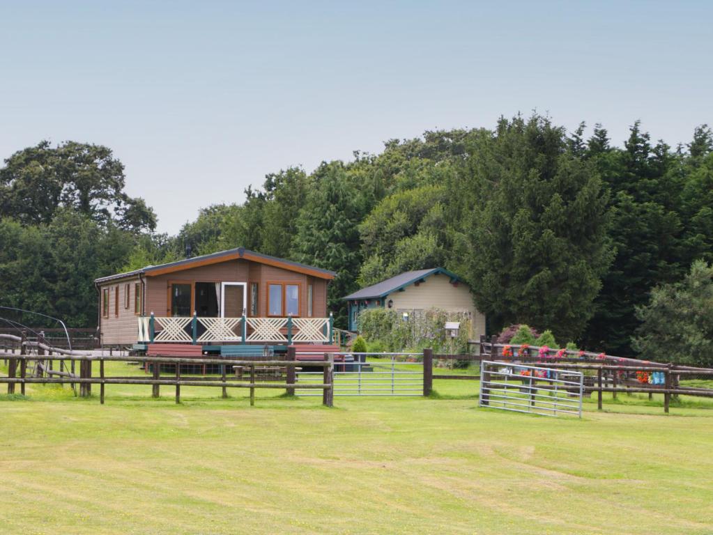 a small house in a field next to a fence at Hill View, Lilac Lodge in Wareham