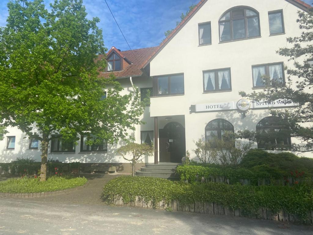 un edificio blanco con un árbol delante en Hotel Spitze Warte, en Rüthen