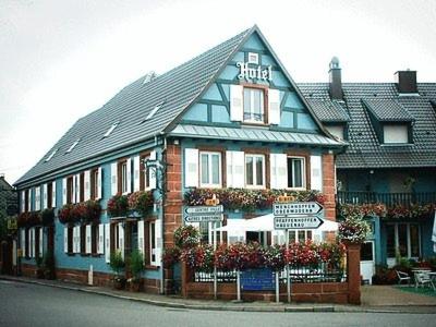 un bâtiment bleu et blanc au coin d'une rue dans l'établissement Logis Hotel Aux Comtes De Hanau, à Ingwiller