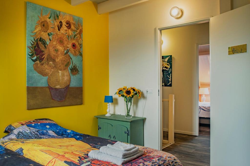 un dormitorio con una pintura de un jarrón de flores en Het Atelier Huis en Maasbommel