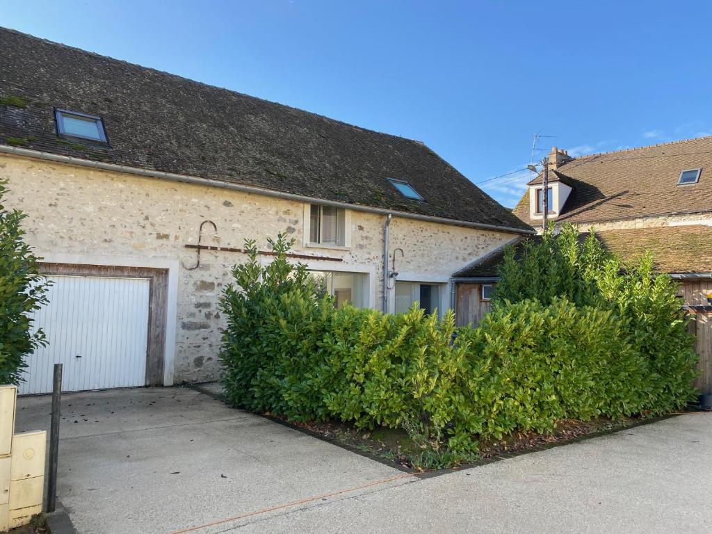 una casa de ladrillo con garaje y algunos arbustos en Les gîtes de Machault, en Machault