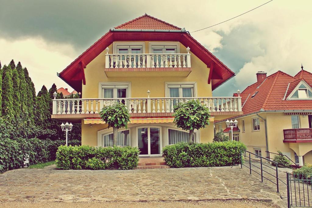una casa amarilla con techo rojo en Vesta Apartments, en Hévíz