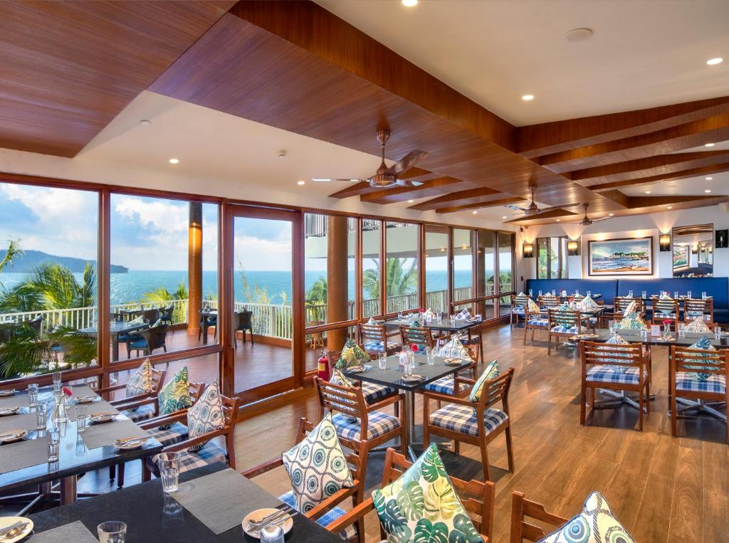 a dining room with tables and chairs and windows at Welcomhotel by ITC Hotels, Bay Island, Port Blair in Port Blair