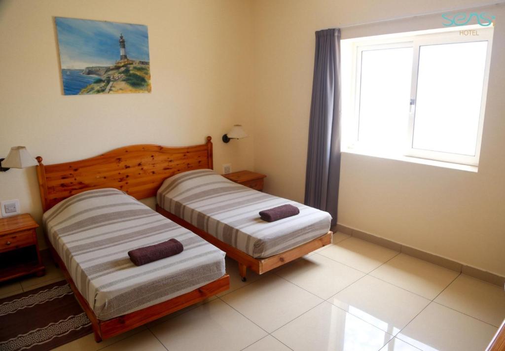 two beds in a room with a window at Sensi Hotel in Marsaskala