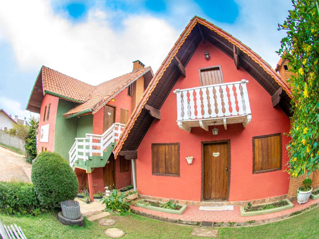 a red house with a balcony on top of it at Villa da Vila in Monte Verde