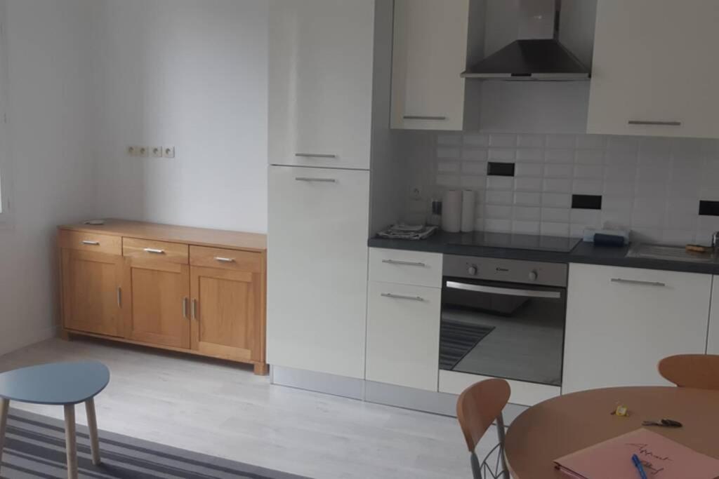 una cocina con electrodomésticos blancos, mesa y sillas en Elbeuf etg1 droite Sweet Home Netflix wifi, en Elbeuf