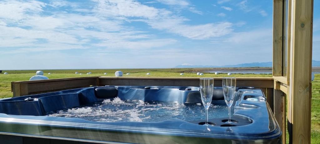 una bañera de hidromasaje con agua y copas de vino. en Hítarneskot Holiday Home en Hítarneskot