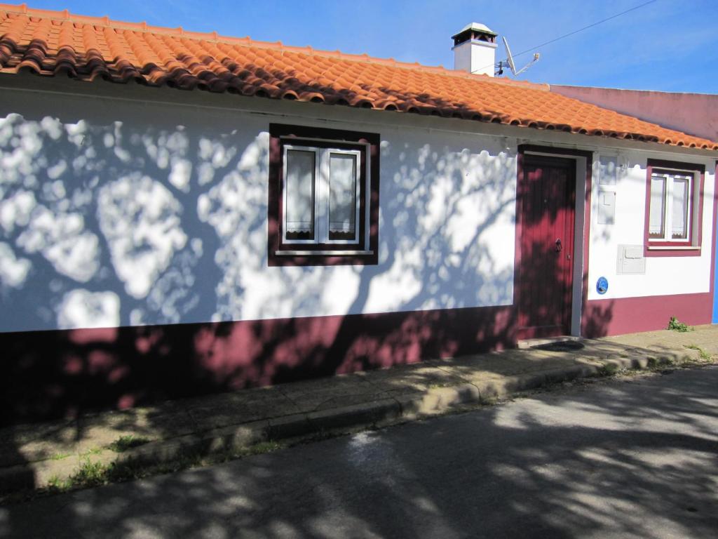 uma casa branca com um telhado laranja e uma porta vermelha em Casa Alentejana em São Teotónio