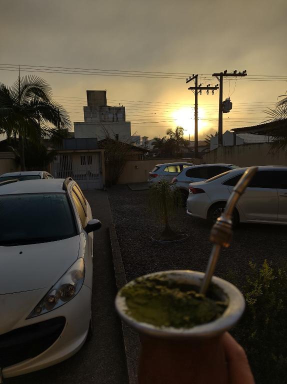 a person holding a drink in a cup in a parking lot at Hospedaria Nossa Casa in Braço do Norte