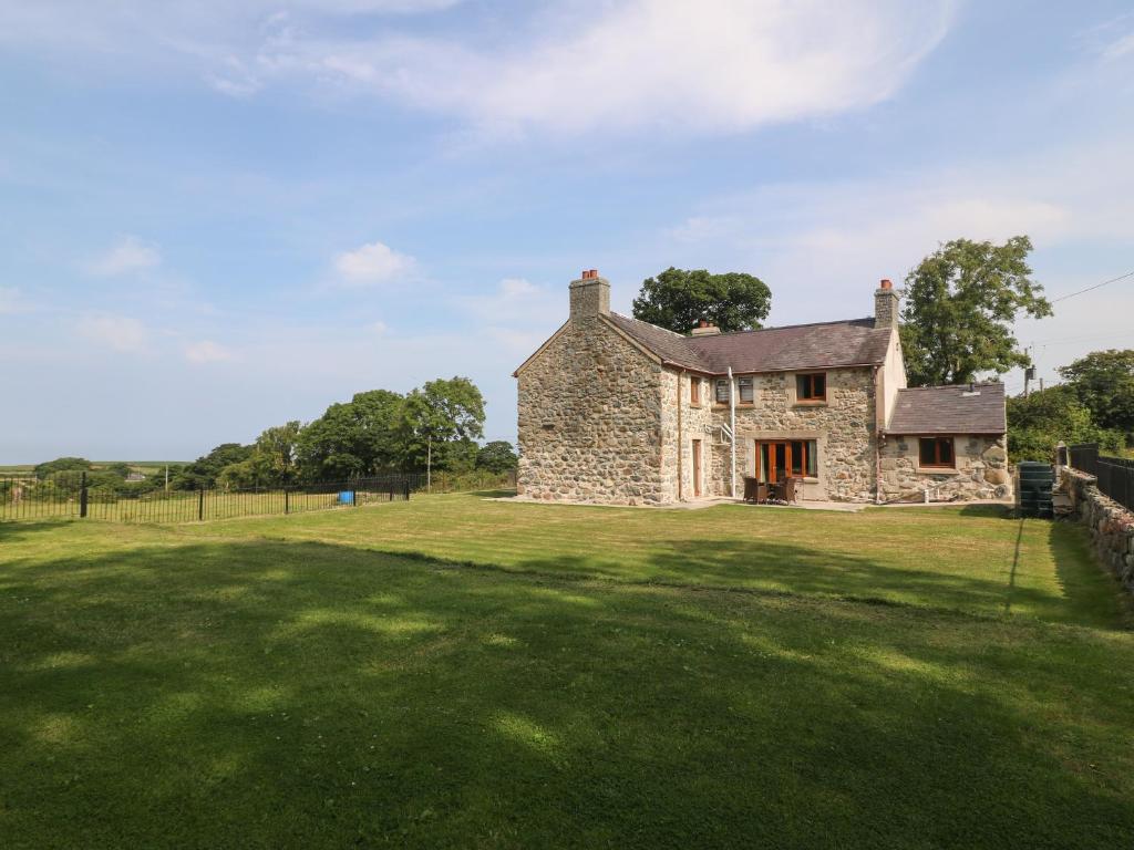 an old stone house on a grass field at Y Berth Ddu Farmhouse in Caernarfon