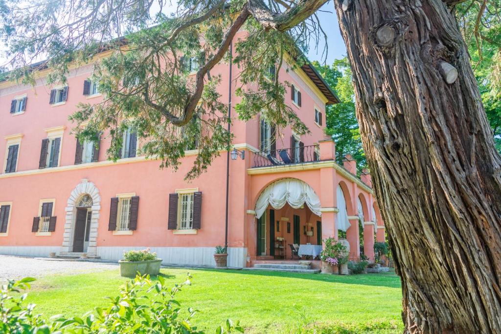 een roze gebouw met een boom ervoor bij Country House Villa Poggiolo in Pilonico Materno