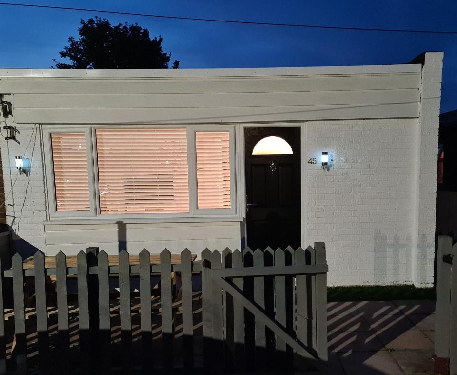 una casa blanca con una puerta y una valla en Large Brick Chalet sleeps 6 mins to beach and amusements en Leysdown-on-Sea