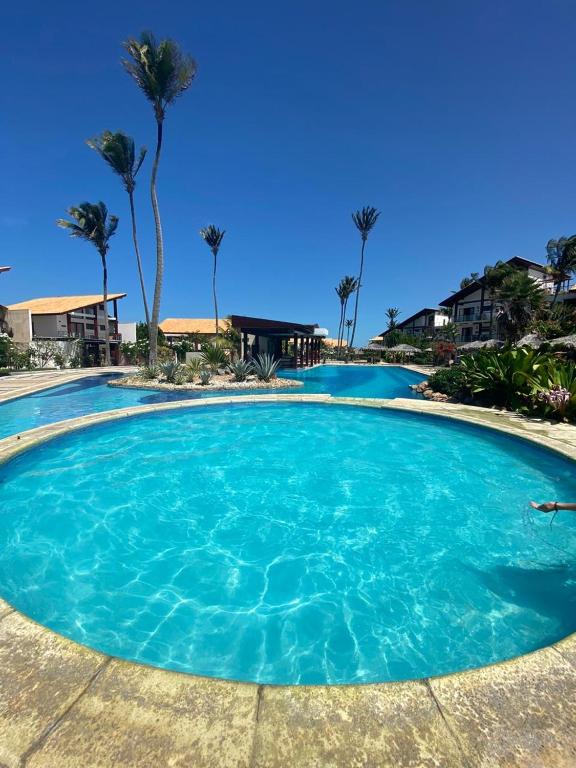 a large blue pool with palm trees in the background at Taiba Beach Resort 03 Apto 2 quartos in São Gonçalo do Amarante