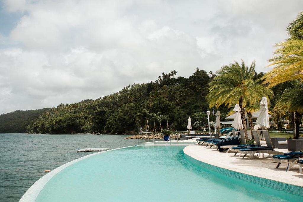 a swimming pool next to a body of water at Ocean View Villa/Luxury Puerto Bahia Resort/Samaná in Santa Bárbara de Samaná