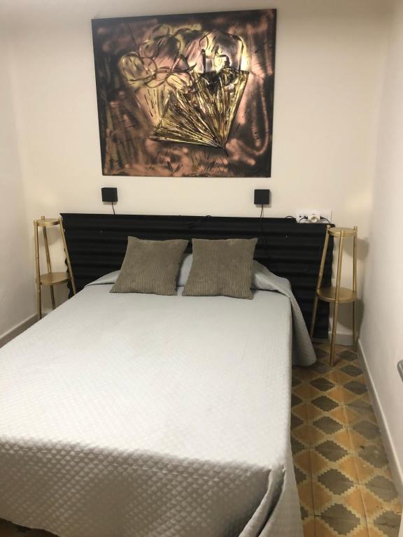 Un dormitorio con una cama blanca con un cuadro encima. en Hostal Sant Marti premium, en Puig-reig