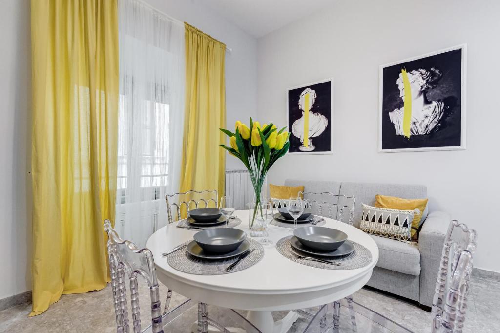 a white dining room with a white table and yellow curtains at CRYSTAL TREVI FOUNTAIN - romedreamhome in Rome