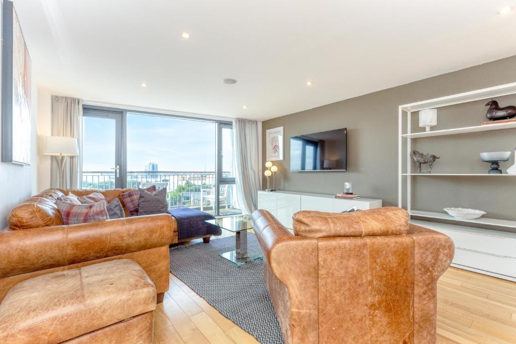 a living room with leather furniture and a large window at SECC Hydro Executive 7 Apartment in Glasgow