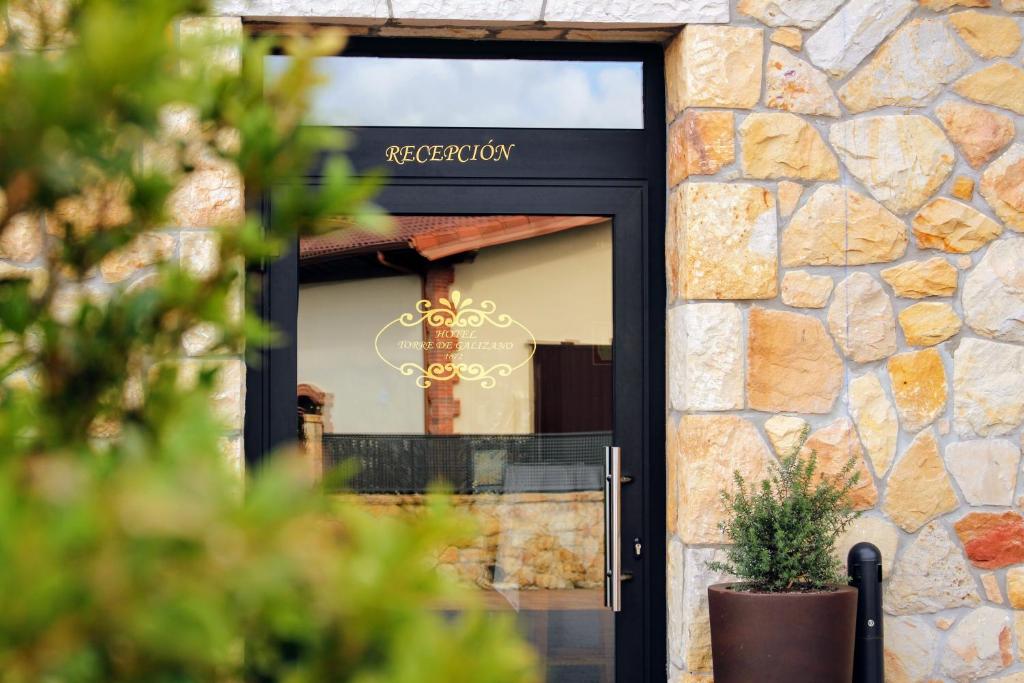 a door to a restaurant with a stone wall at Hotel Gastronómico Torre de Galizano in Galizano