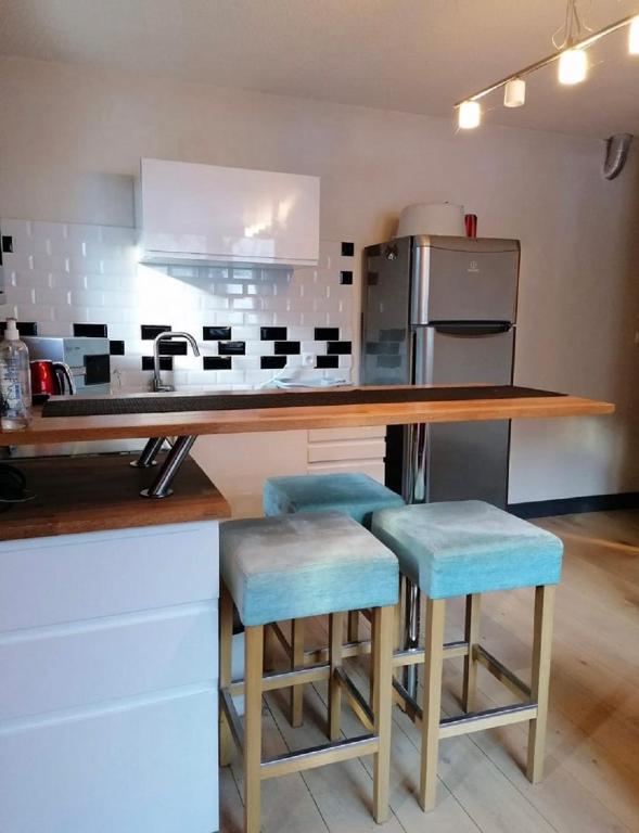 a kitchen with a counter and some blue stools at Très bel appartement face au lac de Bozel in Bozel