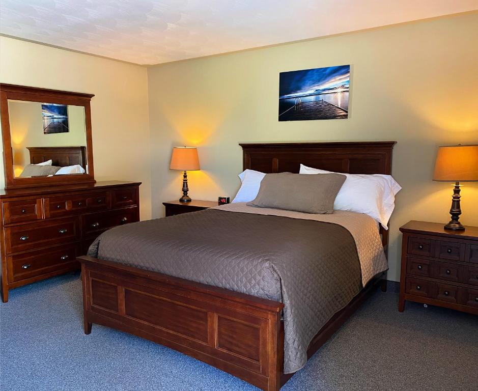 a bedroom with a bed and two dressers and a mirror at Manitoulin Inn in Mindemoya