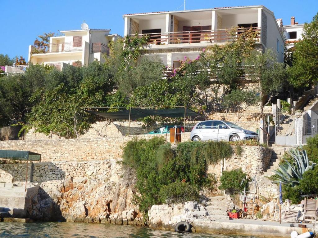 une maison sur une colline à côté d'une masse d'eau dans l'établissement Apartments Ivan - 15 m from beach, à Vinišće