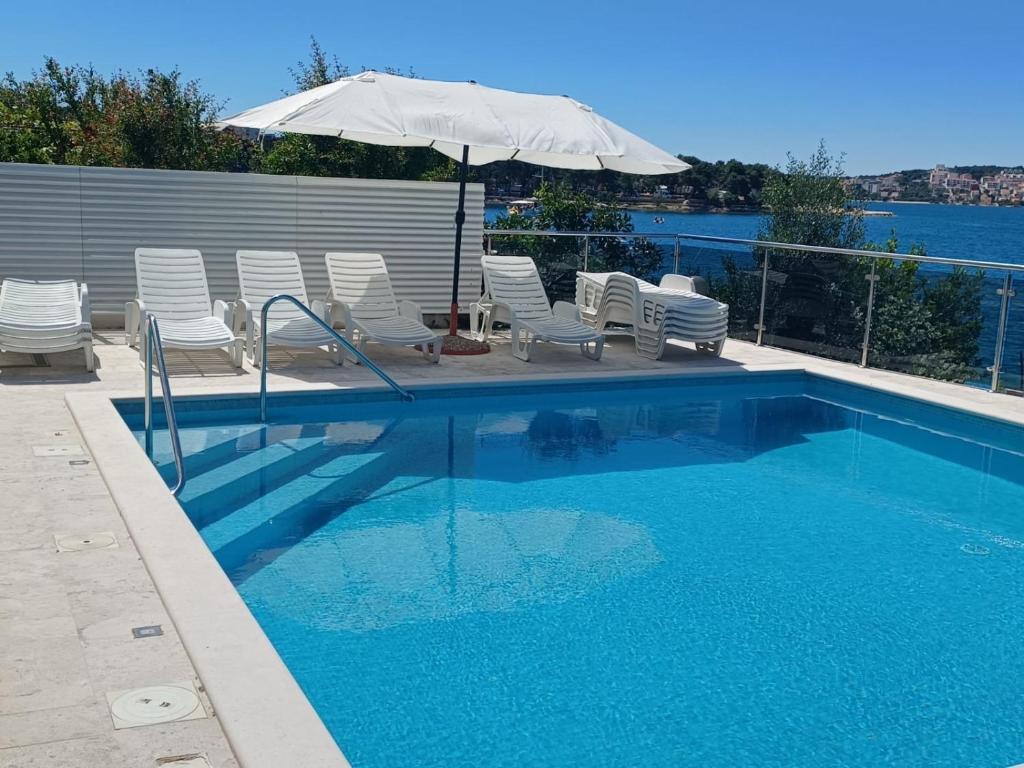 uma piscina com cadeiras e um guarda-sol em Apartments Marija - 10m from beach em Trogir