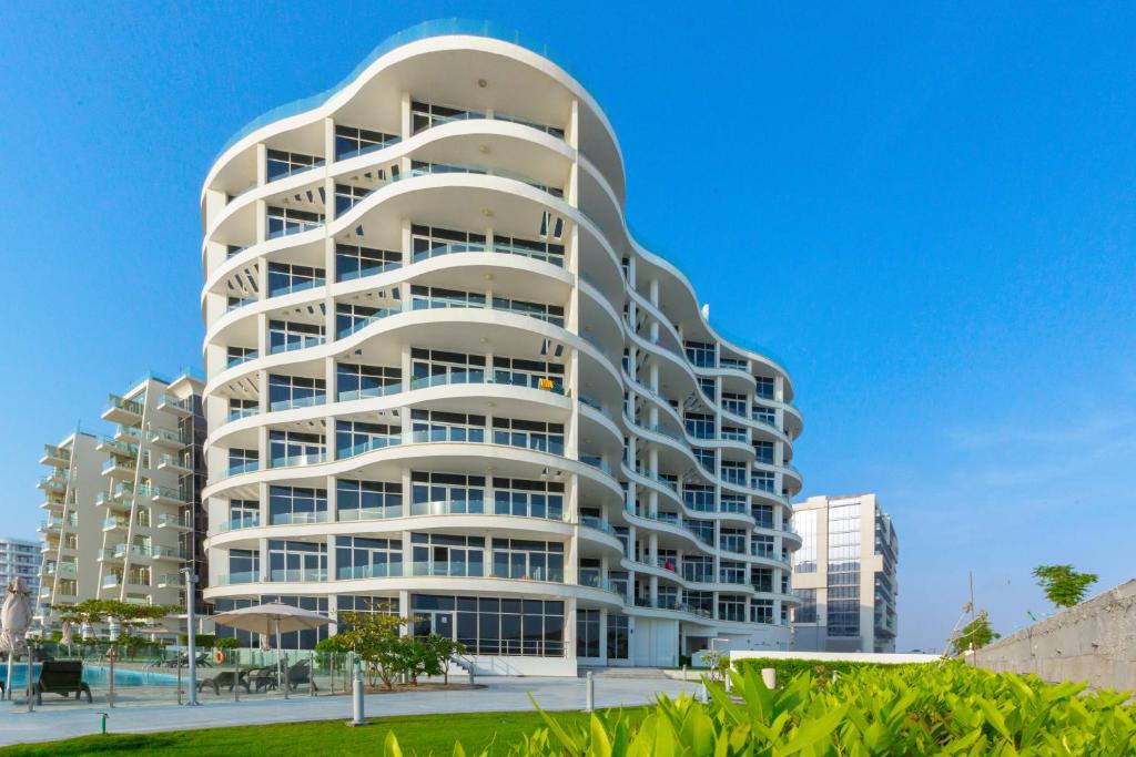 a tall white building with a lot of windows at Palm Chateau Apartments Dubai in Dubai