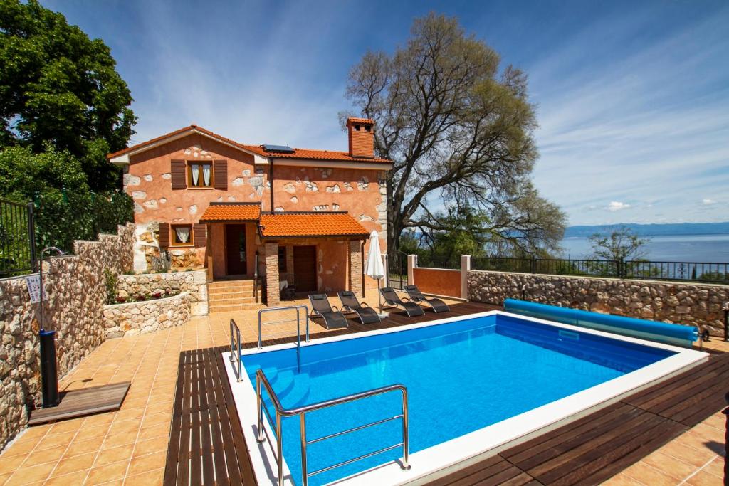 a swimming pool in front of a stone house at Villa Milena in Brseč