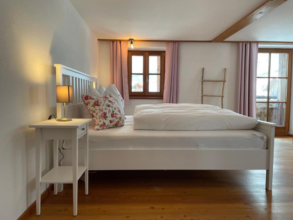 - une chambre avec un lit blanc, une table et une lampe dans l'établissement Bergien, à Halblech