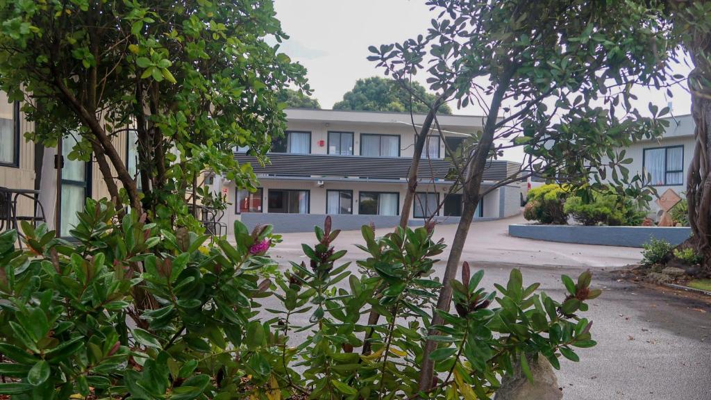 a building with a lot of trees in front of it at Fiesta Court Motel in Whanganui